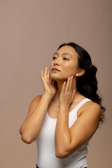 Asian woman with dark hair touching face with both hands, copy space