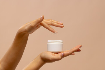Hands of asian woman using jar of beauty cream with copy space