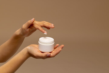 Hands of asian woman using jar of beauty cream with copy space