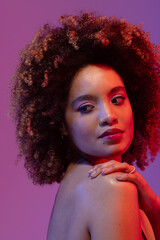 Biracial woman with curly hair with hand on shoulder on purple background