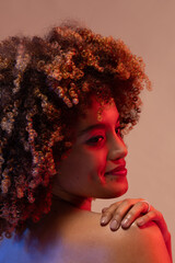 Smiling biracial woman with curly hair and hand on shoulder in red light