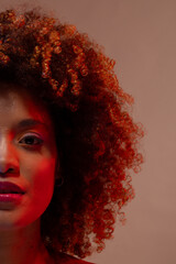 Half portrait of biracial woman with curly hair in red light