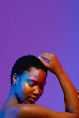 African american woman with short hair and colourful make up touching head, eyes closed, copy space
