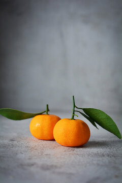 two fresh orange fruits with leaves. mandarin orange on grey and texture background 