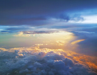 Stunning arial view of Golden sunrays and rays of sunlight over the clouds on the blue sky background looking out of aircraft window. Scenic view above the clouds