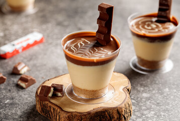 Kinder chocolate cheesecake served in cup isolated on wooden board top view cafe cheese cake food dessert
