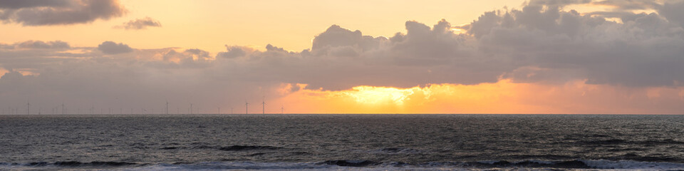 Banner sunset over the sea, windmills along the horizon