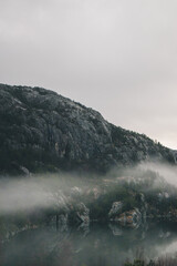 Mountains in Norway. Lake, beach and mountains near Preikestolen. With fog a fairytale picture.