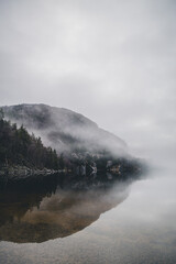 Mountains in Norway. Lake, beach and mountains near Preikestolen. With fog a fairytale picture.