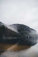 Mountains in Norway. Lake, beach and mountains near Preikestolen. With fog a fairytale picture.