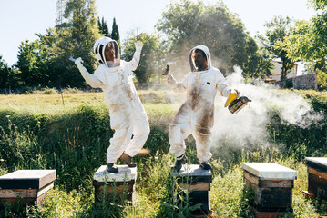 Joyful apiarist laughing and dancing during work in countryside