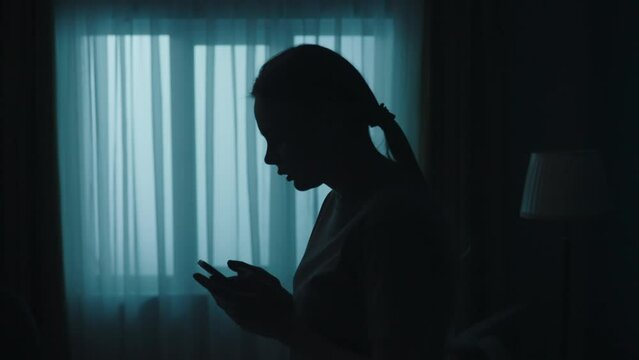 Young shocked woman owner comes in the dark room, sees something strange and calls the police on smartphone. Crime scene creative concept.