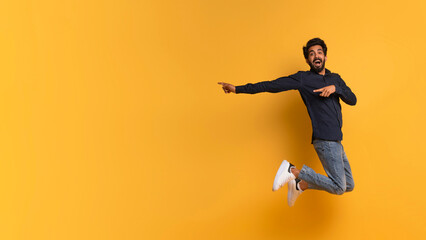 Fototapeta na wymiar Great Offer. Excited indian man pointing aside while jumping up in air