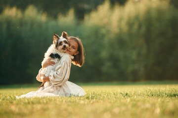 Cute little girl is on the field with dog