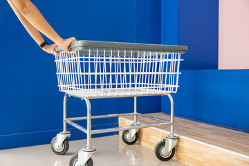 Laundry and housework. metal cart parked use for laundry at convenience store for support customer, Woman hands holding shove empty new white trolley cart, Laundromat convenience store concept - Powered by Adobe