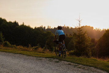 Professional athlete cyclist ride carbon gravel bike with beautiful mountain view at sunset. Cycling exploration adventure.Cyclist practicing on gravel road.Man cycling in the nature.Bucegi Mountains