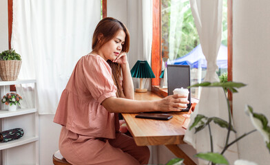 A happy mixed-race female at a cafe using a laptop in hand and a paper cup of coffee. young white woman with long hair sitting in a coffee shop busy working on her laptop.