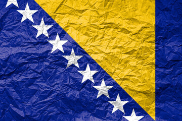 Flag of Bosnia and Herzegovina on crumpled paper. Textured background.