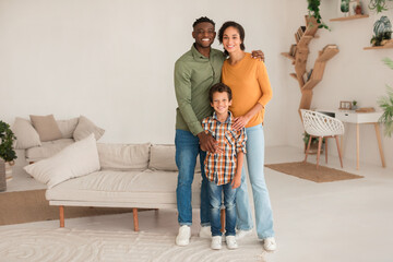 Smiling Multiracial Parents Hugging Their Little Son Standing At Home