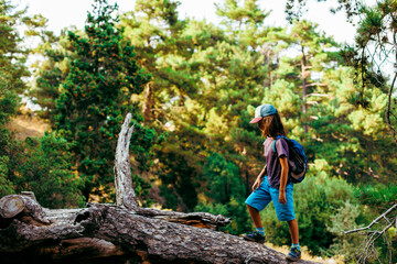 boy walks on top of a fallen tree in the forest. Children's leisure, a happy child climbs a tree and has fun.