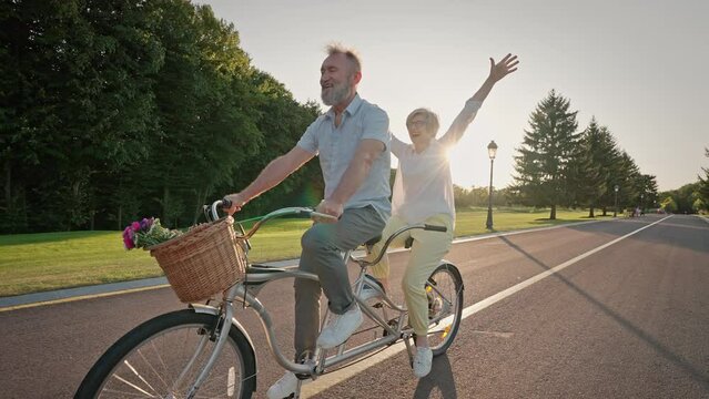 Senior spouse riding tandem bicycle together on fresh air