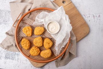 Air fried breaded chicken nuggets in a basket with dip and ready to serve