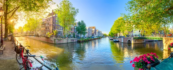 Foto auf Acrylglas Amsterdam Soul of Amsterdam. Early morning in Amsterdam. Ancient houses, bridges, traditional bicycles, canals, boats,  and the sun shines through the trees. Panoramic view with all the sights of Amsterdam.