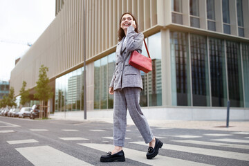 Naklejka premium Successful Young Businesswoman Communicating Talking By Cell Phone Walking Outside