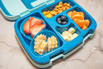 School lunch bento box with ham and cheese, fruit, and crackers.