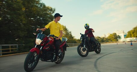 Driving instructor and his student are driving on a motorsport training ground in sunny weather. Guy instructor in a yellow t-shirt