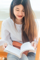 Happy asian student  young woman thinking with book in library