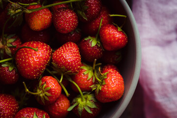 Red ripe strawberry in gray bowl on the rustic background. Selective focus. Shallow depth of field.