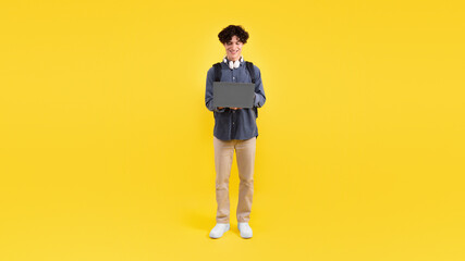 Student Guy Using Laptop Computer Over Yellow Studio Background