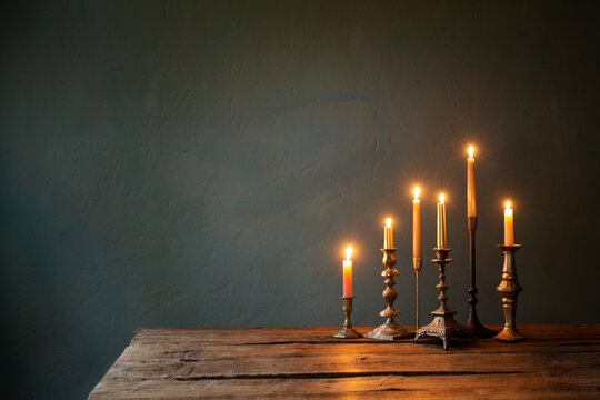 burning candles in vintage candlesticks on dark background