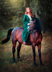 Portrait of  a beautiful red haired girl in green medieval dress with horse. Fairy tale story about brave heart woman.Amazing model looking at camera.Warm art work