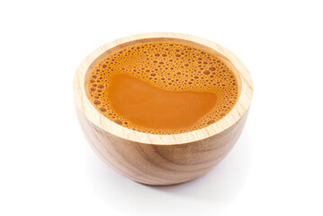 Hot milk tea in a wooden cup on white
