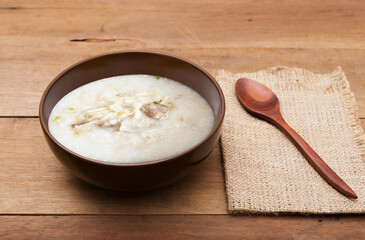 Traditional chinese porridge rice gruel in brown bowl with wooden spoon