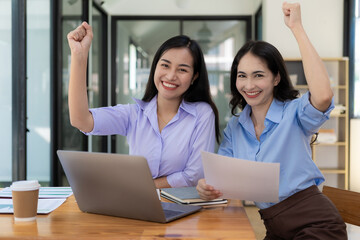 Two businesswomen expressed their joy with smiling faces. Raised hands showing joy after successful business, working in the office.