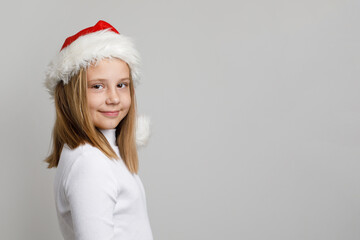 Cute cheerful child girl young fashion model wearing Santa hat on white background with copy space