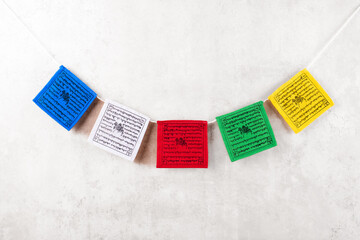 Colorful Tibetan buddhist prayer flags with mantras by Nepal on a grey background, copy space, top...