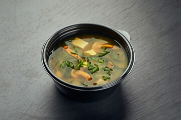 Traditional Japanese miso soup with mushrooms in a plastic delivery bowl