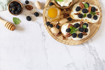 Healthy breakfast toasts. Keto diet sandwiches. Keto snack. Sweet bruschetta with cheese and berries blackberry ricotta and honey on marble table. View from above. Copy space.