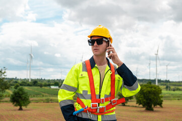 A smart engineer with protective helmet on head, using smartphone at electrical turbines field