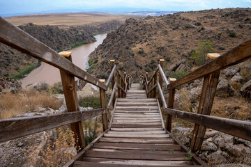 Wooden railing stairs descending from cliff to river