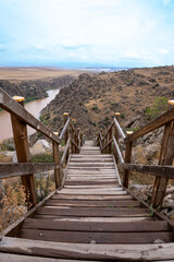 Wooden railing stairs descending from cliff to river
