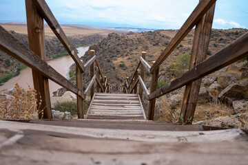 Wooden railing stairs descending from cliff to river