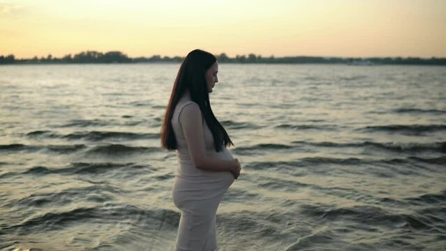 A pregnant woman takes a leisurely stroll by the w