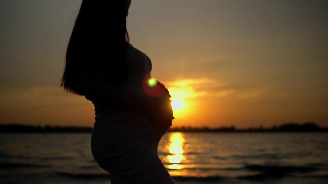 The silhouette of an expectant mother, lovingly to