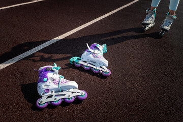 white roller skates lie on track against the background of a roller and a shadow