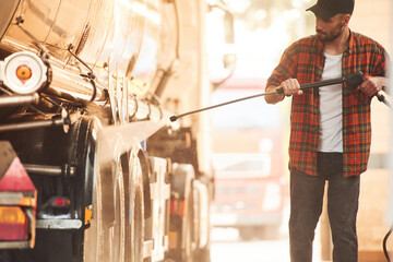 Process of washing the vehicle. Young truck driver in casual clothes
